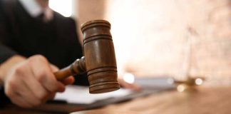 Judge with gavel on wooden desk courtroom setting