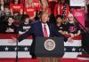 Person speaking at podium with crowd behind them.