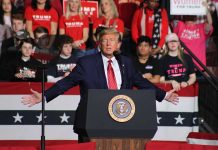 Person speaking at podium with crowd behind them.