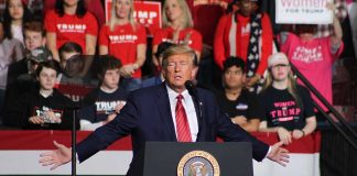 Person speaking at podium with crowd behind them.