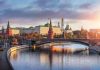 Kremlin by river at sunset with bridge.