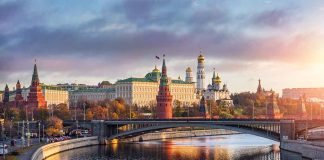 Kremlin by river at sunset with bridge.