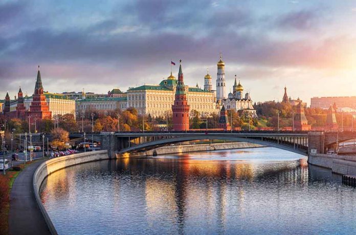 Kremlin by river at sunset with bridge.