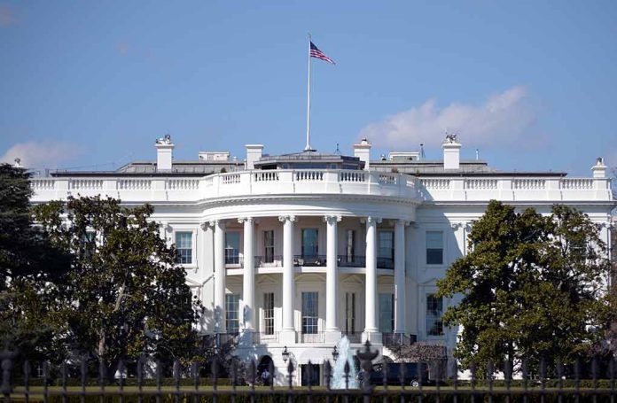 White House with American flag flying, daytime.