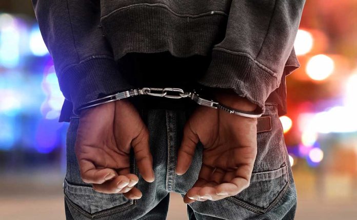 Person in handcuffs with colorful lights in background.