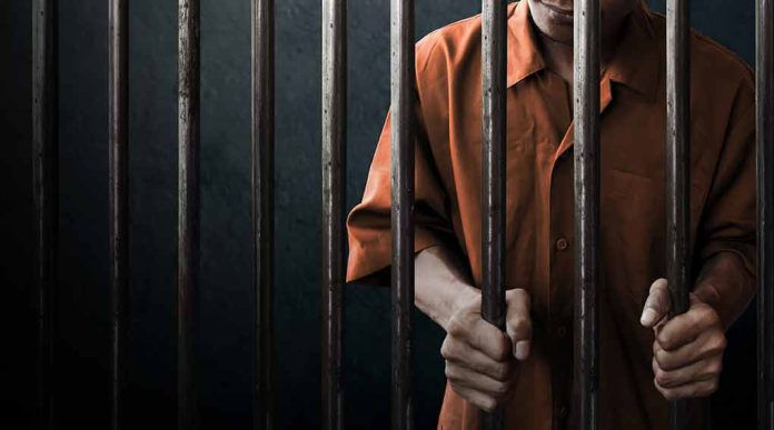 Person wearing orange clothing behind prison bars