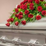 Silver casket with red rose arrangement on top.