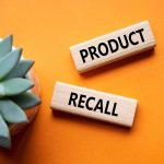 "Product recall" sign near succulent on orange background.