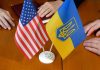 American and Ukrainian flags with two people nearby