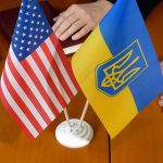 American and Ukrainian flags with two people nearby