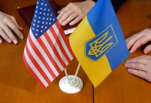 American and Ukrainian flags with two people nearby