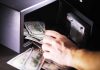 Hand putting cash into a safe.