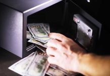 Hand putting cash into a safe.