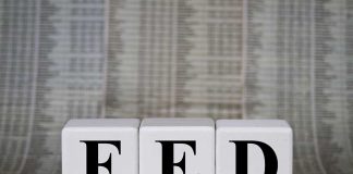 Blocks spelling FED against financial chart background.
