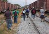 People walking along train tracks carrying backpacks
