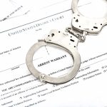 Handcuffs on top of arrest warrant document