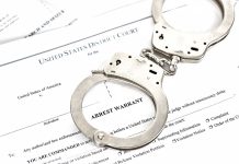 Handcuffs on top of arrest warrant document