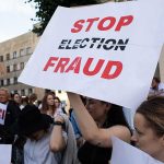 People holding Stop Election Fraud protest signs.