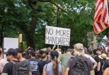 Crowd holds No More Mandates sign at protest