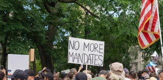 Crowd holds No More Mandates sign at protest