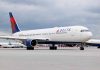 Delta Airlines airplane on airport runway, cloudy sky