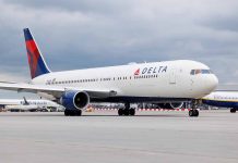 Delta Airlines airplane on airport runway, cloudy sky