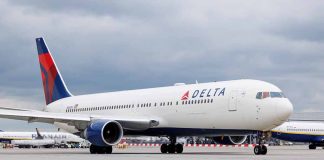 Delta Airlines airplane on airport runway, cloudy sky
