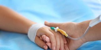 Two hands holding one with medical IV attached