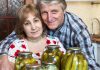 Older couple smiling with jars of pickles
