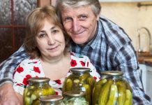 Older couple smiling with jars of pickles