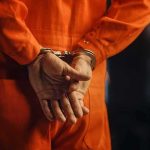 Person in orange jumpsuit with handcuffs behind back