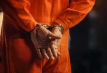 Person in orange jumpsuit with handcuffs behind back