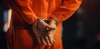 Person in orange jumpsuit with handcuffs behind back