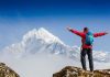 Hiker with arms outstretched in front of snowy mountains