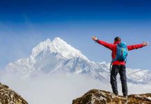 Hiker with arms outstretched in front of snowy mountains