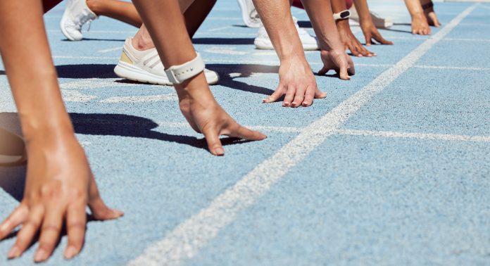 ready to compete in track and field_2175132111.jpg featured image Athletes at starting line on blue track race