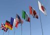 Flags of seven countries against clear blue sky