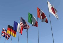 Flags of seven countries against clear blue sky