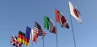 Flags of seven countries against clear blue sky