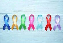 Colorful awareness ribbons on light wooden background