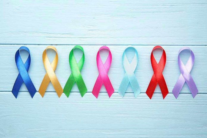 Colorful awareness ribbons on light wooden background
