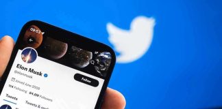Hand holding phone displaying Twitter profile