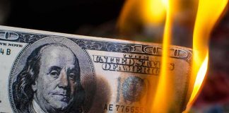 Hundred dollar bill burning with orange flames