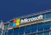 Microsoft logo on a modern corporate building against a blue sky