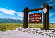Entrance sign for Grand Teton National Park with mountains in the background