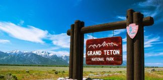 Entrance sign for Grand Teton National Park with mountains in the background