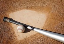 A baseball bat and ball resting on a baseball diamond