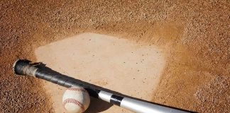 A baseball bat and ball resting on a baseball diamond