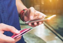 Person holding a smartphone and a credit card, preparing for a digital transaction