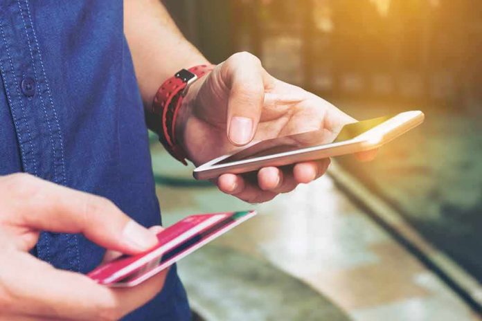 shutterstock_540545581.jpg Person holding a smartphone and a credit card, preparing for a digital transaction